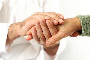 Male Physician is comforting a patient by holding their hand