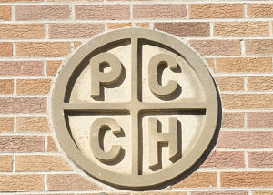 Brick wall that has a circle with the letters PCCH