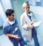 Male Nurse and Female Physician walking and talking in a hospital hallway